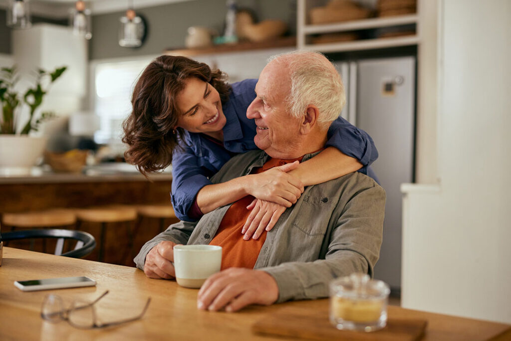 Woman with her arms around an elderly family member at a table
